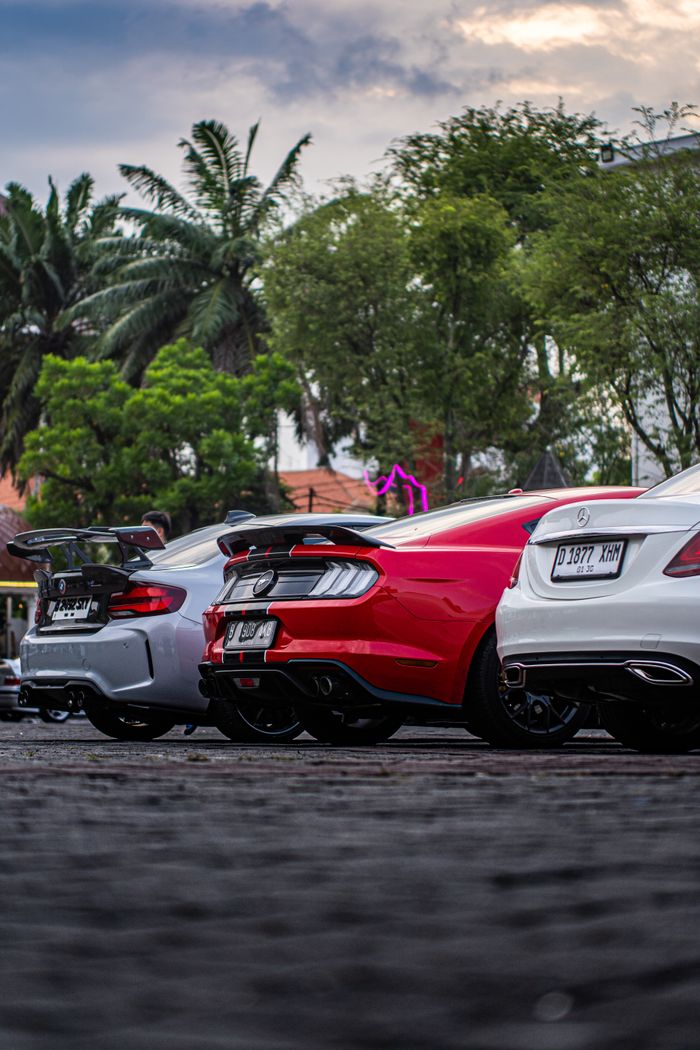 Row of high-end supercars parked outdoors in Semarang, Indonesia with tropical trees in background.