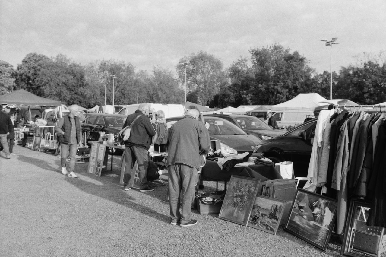 A bustling flea market scene captured in black and white, showcasing vintage items and shoppers.